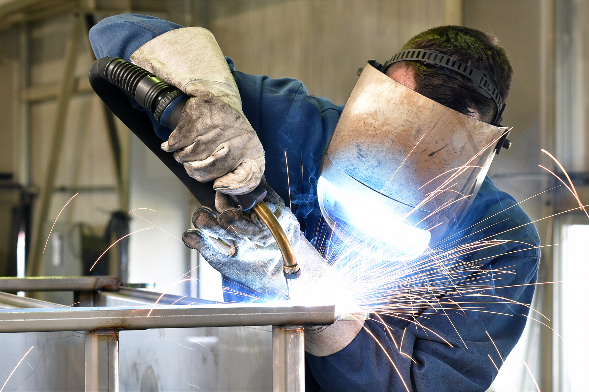 Man welding pieces of metal together wearing protective PPE